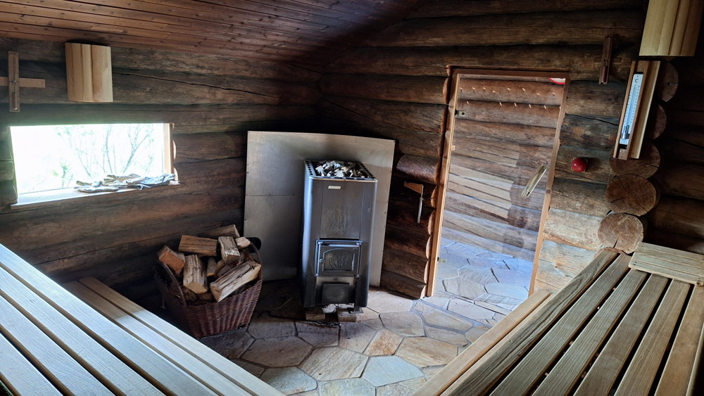 Die Sauna von innen. Der Ofen zum Heizen und ein Fenster mit Blick auf den See.
